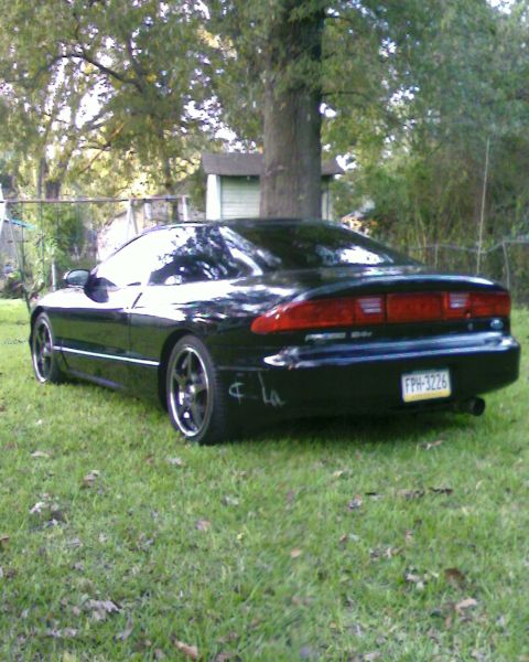 1996 Ford Probe - Rear view of a black 1996 Ford Probe with aftermarket wheels, parked on a grassy lawn.