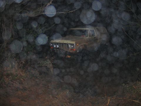 1992 Ford Mustang - A Ford Bronco navigates a muddy, wooded trail in low light conditions.