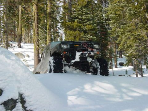 1986 Ford Bronco - A heavily modified off-road vehicle navigates a snowy forest trail.