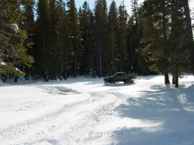 Pickup truck driving in snow with tire tracks visible