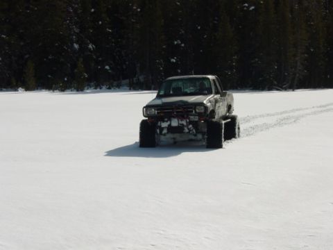 1986 Ford Bronco - A lifted pickup truck navigates a snowy landscape.