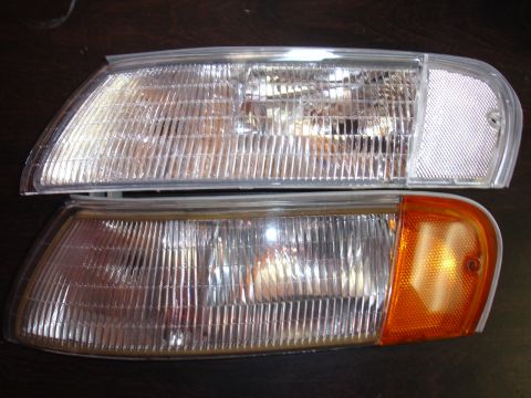 1993 Ford Taurus - A close-up view of two automotive headlights, one clear and one with an amber corner signal.