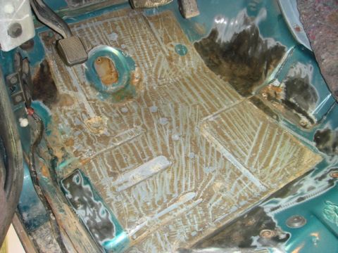 1996 Ford Bronco - The interior floor of a vehicle shows areas of rust and preparation for repair.