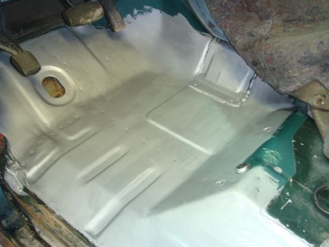 1996 Ford Bronco - The interior floor of a vehicle has been treated with primer, revealing the underlying metal structure and some original green paint.
