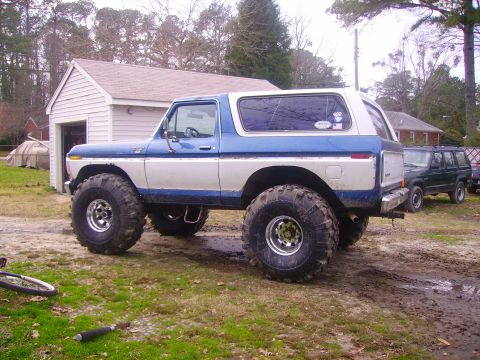 1978 Ford Bronco - A lifted 1978 Ford Bronco with custom wheels and tires sits outside a garage, with another SUV visible in the background.