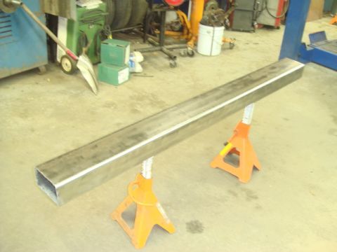1996 Ford Bronco - A long metal beam is held up by two orange jack stands in a garage setting.
