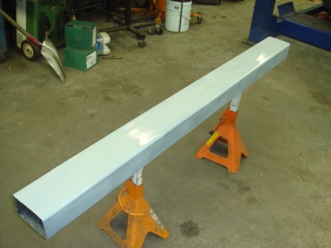 1996 Ford Bronco - A metal beam is elevated on jack stands within a garage setting, with tools and equipment visible in the background.