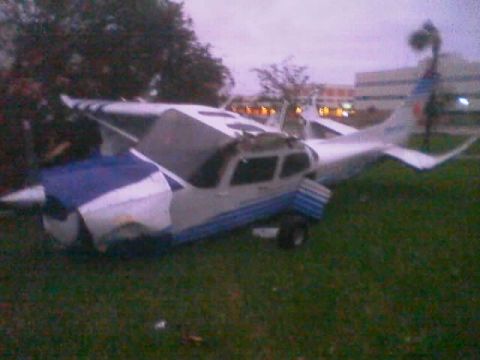 1989 Ford Bronco - An airplane lies damaged on a grassy area, with buildings visible in the background.
