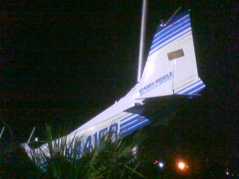 1989 Ford Bronco - The tail section of an airplane, marked with 'EMBRY-RIDDLE' and blue stripes, is visible against a dark background.