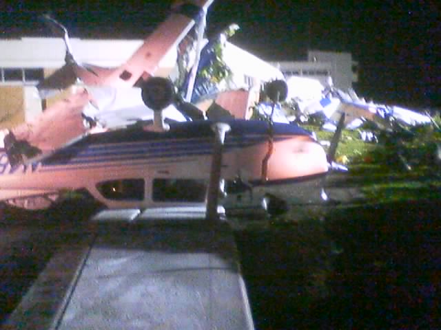Night photo of damaged white light aircraft with blue stripes piled together