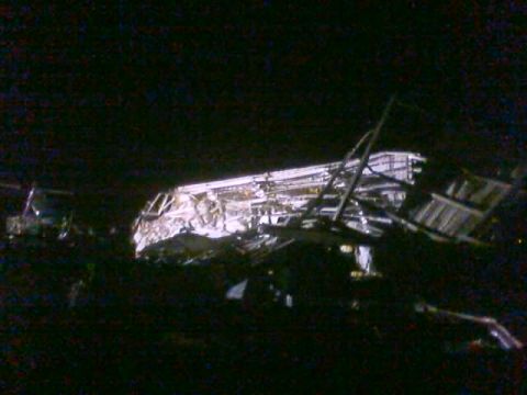 1989 Ford Bronco - The aftermath of a destructive event shows a collapsed structure and surrounding vehicles in darkness.
