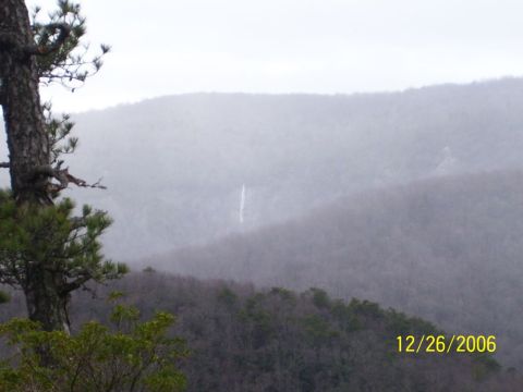 1993 Ford Bronco - A distant waterfall cascades down a misty mountain slope, with a pine tree in the foreground.