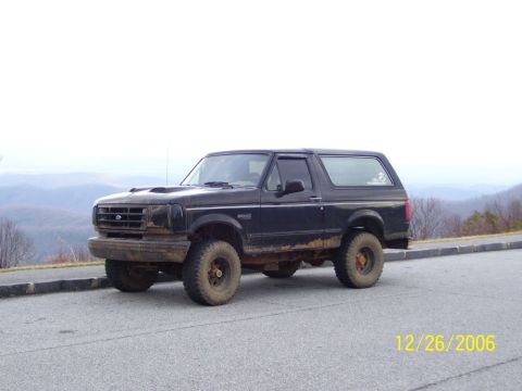 1993 Ford Bronco - A black 1993 Ford Bronco is parked on the side of a road with a mountainous landscape behind it.