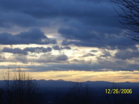 1993 Ford Bronco - The sky is filled with dark clouds as the sun sets behind a mountain range.