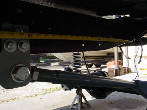 1979 Ford Bronco - Close-up of vehicle suspension parts being measured, with a boat on a trailer visible in the background.