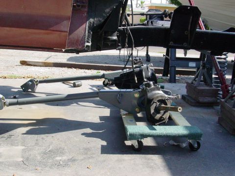 1979 Ford Bronco - Vehicle chassis and suspension components are laid out on dollies, with a maroon door visible in the background.