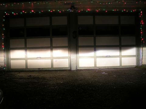 2004 Mazda 6 - Headlights shine on two garage doors adorned with festive holiday lights.