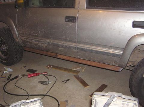 2000 Chevrolet Tahoe - Custom wooden sliders are being fitted to the side of a silver SUV, with welding tools and materials scattered on the garage floor.