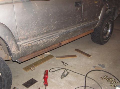 2000 Chevrolet Tahoe - Custom metal sliders are being installed on the side of a dirty 2000 Chevrolet Tahoe.