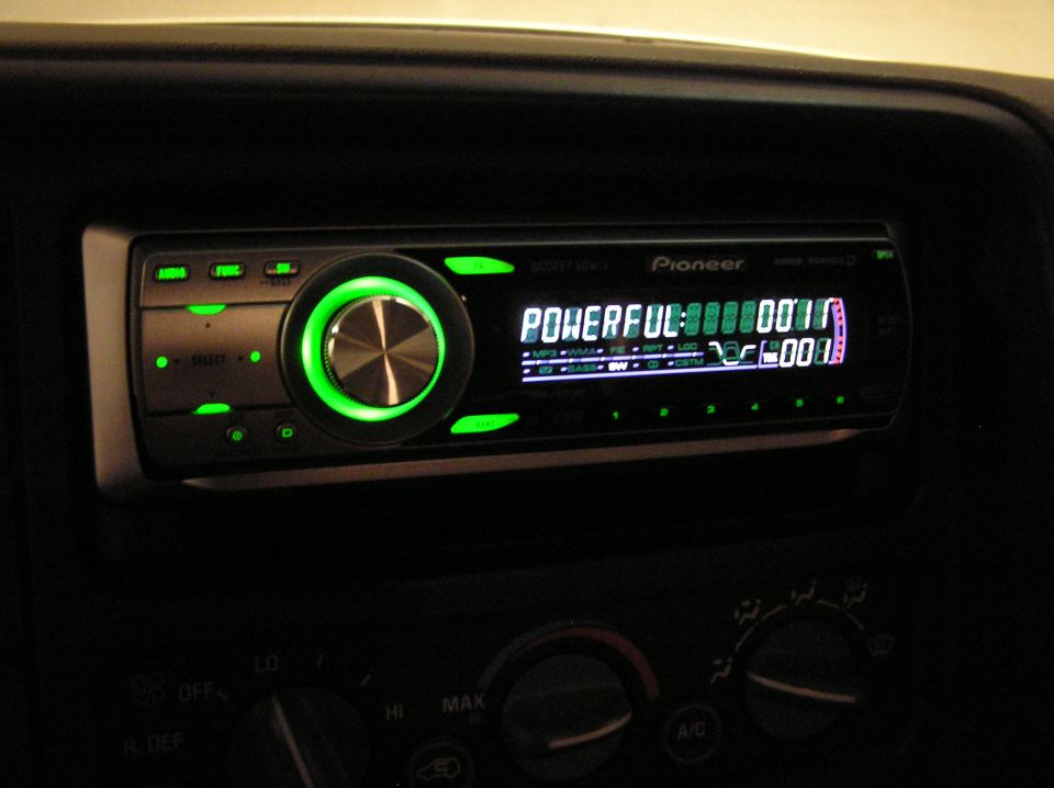 Car stereo with green lighting, showing 'POWERFUL' and song info
