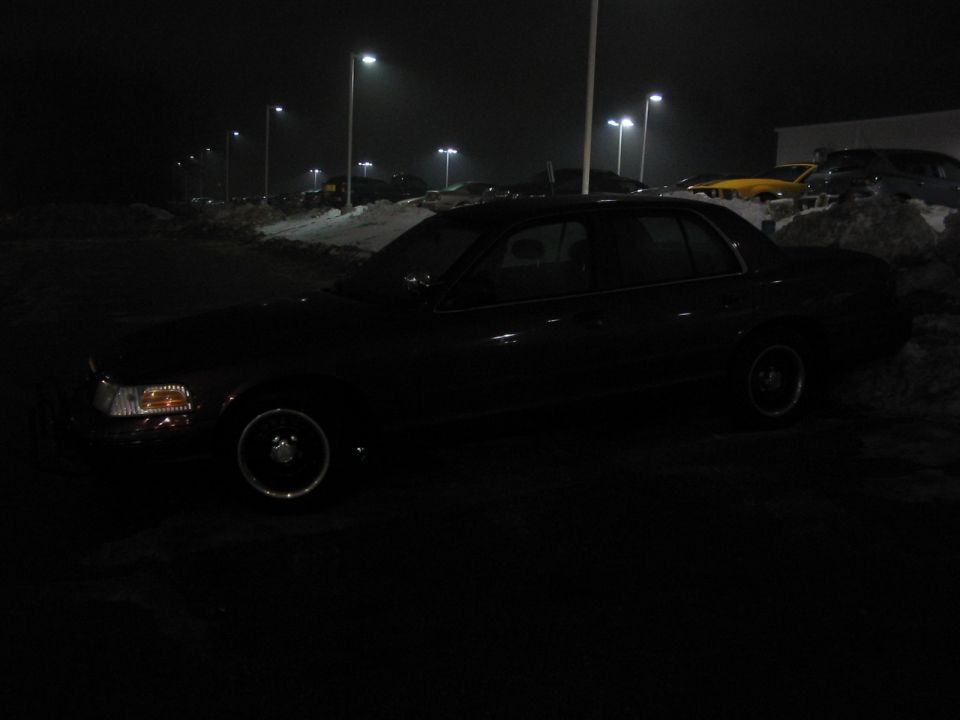 Side view of a black 2001 Ford Crown Victoria parked at night