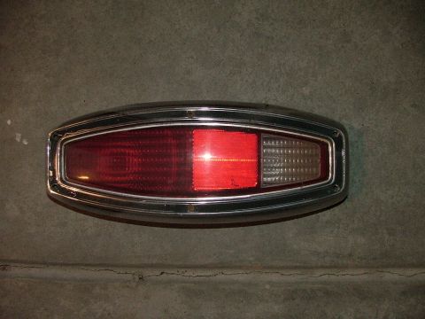 1969 Ford Ranchero - Tail light assembly with chrome trim, red and clear sections, against a concrete background.
