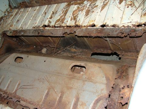 1969 Ford Ranchero - The bed floor of this vehicle is severely rusted, with holes and debris visible.
