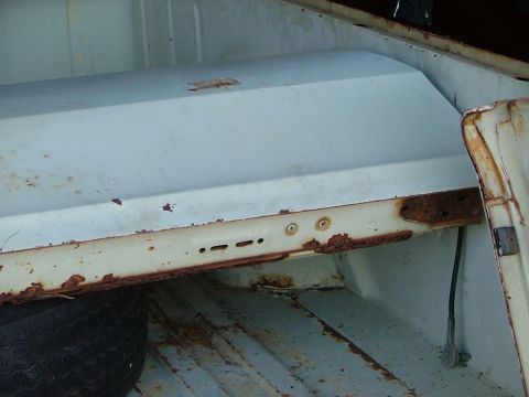 1969 Ford Ranchero - The interior of a vehicle's bed shows significant rust damage and a spare tire, with a watermark at the bottom right.