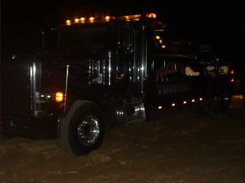 1978 Ford Bronco - Night shot of a black semi-style heavy wrecker with amber cab and running lights lit, purple flame graphics on the hood, chrome wheels, and…