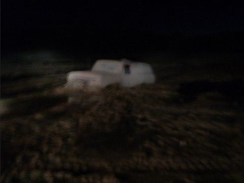 1978 Ford Bronco - A white SUV is stuck in the mud at night, with only its silhouette visible against the dark background.