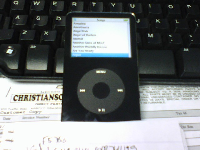 Black iPod Classic on a keyboard and paperwork
