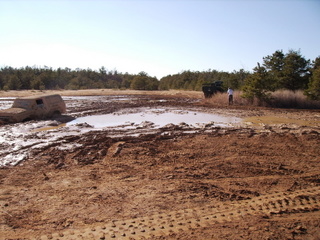1978 Ford Bronco - A vehicle is stuck in a muddy field with trees in the background.