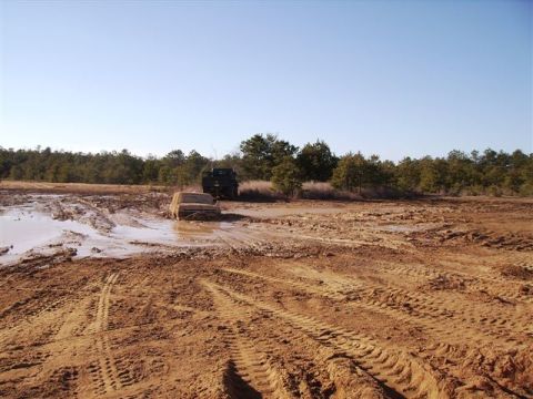 1978 Ford Bronco - A tan SUV is stuck in a muddy field, with a dark vehicle visible in the background.