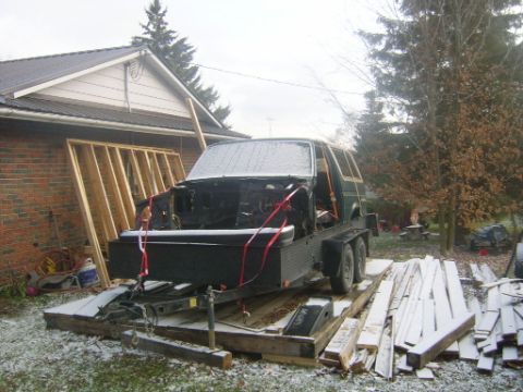 1990 Ford Bronco - An SUV body, missing its front end, is secured to a trailer for transport during a light snowfall.