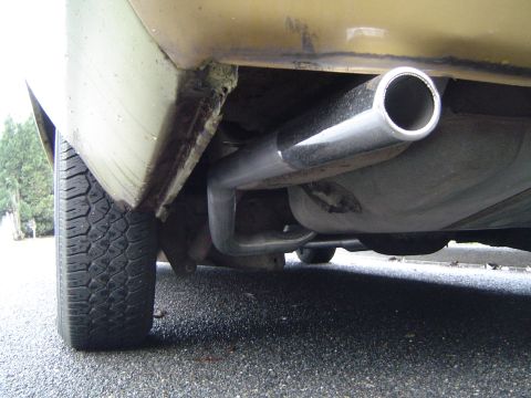 1973 Ford Torino - The underside of a vehicle shows a chrome exhaust pipe extending towards the rear, with a fuel tank visible above it.