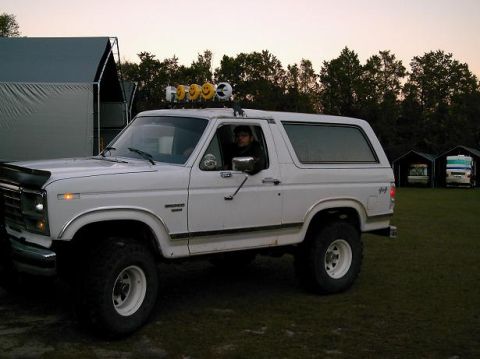 1986 Ford Bronco - White 1986 Ford Bronco with a suspension lift and decorative smiley face lights mounted on the roof rack.