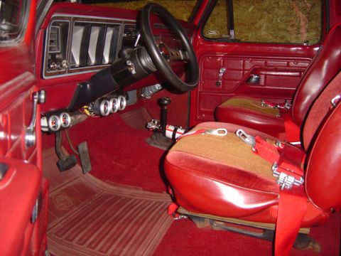 1978 Ford Bronco - The interior of a red 1978 Ford Bronco shows its bucket seats, floor shifter, and added gauges.