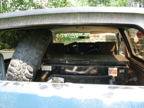 1986 Ford Bronco - View of the interior cargo area of a vehicle, showing a spare tire and a large storage box.