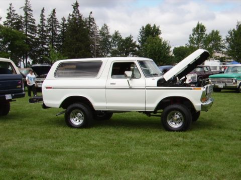 1978 Ford Bronco - A white 1978 Ford Bronco is parked on a grassy field with its hood open, alongside other vehicles.