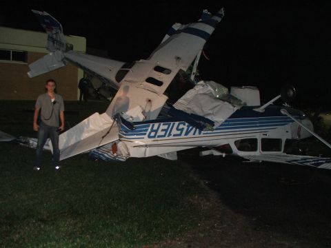 1989 Ford Bronco - A person stands next to a severely damaged aircraft at night.
