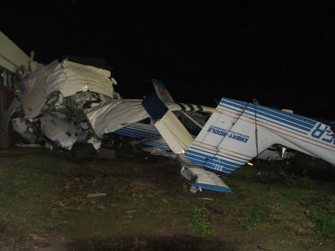 1989 Ford Bronco - A severely damaged airplane lies on its side at night, with debris scattered around the crash site.