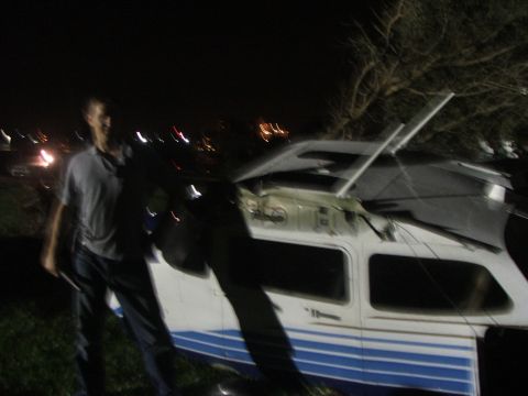 1989 Ford Bronco - An airplane appears to have sustained damage, possibly from a tornado, with a person standing next to it in the dark.