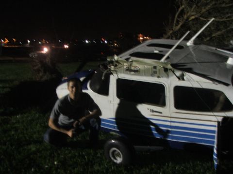 1989 Ford Bronco - A person kneels beside a damaged small aircraft outdoors at night, with city lights in the background.