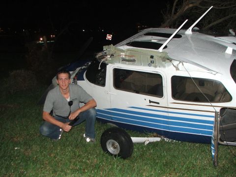 1989 Ford Bronco - A man crouches next to a damaged airplane, which appears to have been involved in an incident.