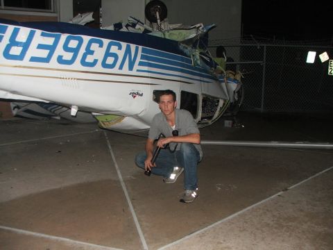 1989 Ford Bronco - A man poses next to a damaged Piper airplane that has crashed on its side.