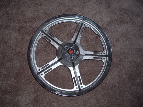 2000 Harley-Davidson Sportster - A chrome motorcycle wheel with a red center cap rests on a brown carpeted surface.