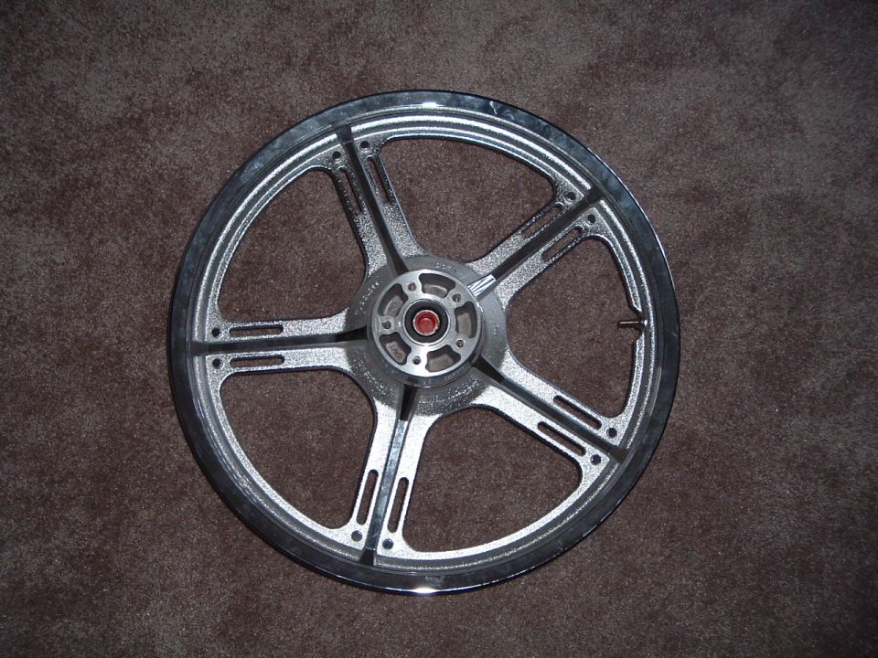 Motorcycle wheel with five spokes, silver finish, on a brown carpet