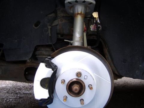 1998 Ford Taurus - Close-up view of a front brake rotor and caliper assembly, highlighting a newly installed drilled and slotted rotor.