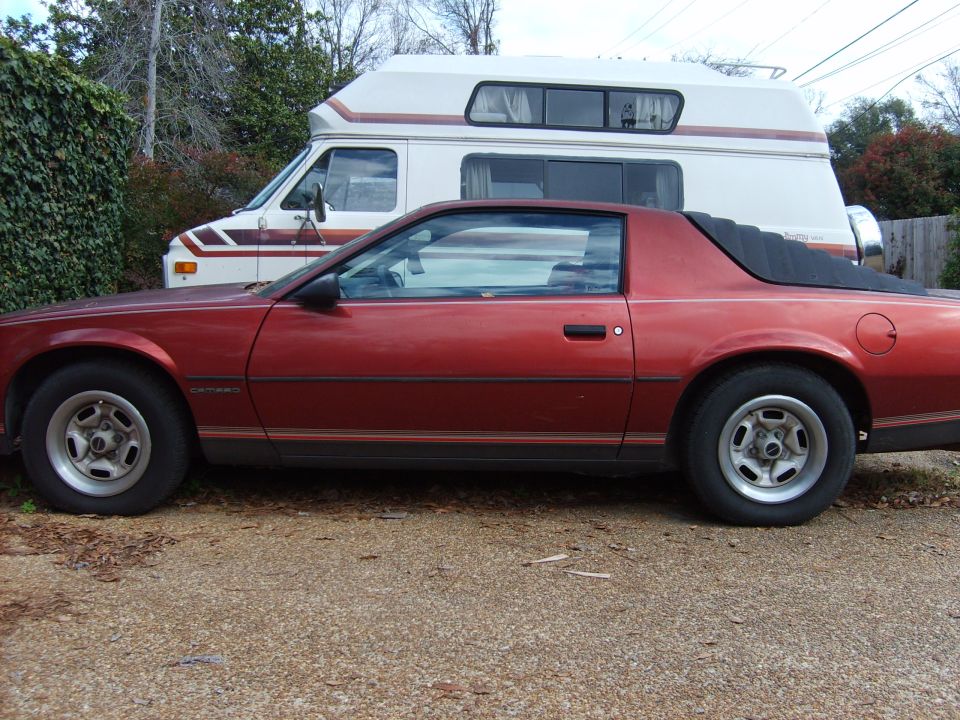 Red coupe parked next to a white camper van