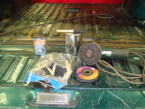 1996 Ford Bronco - Supplies for rust repair, including an angle grinder and wire wheel, are laid out in the bed of a truck.